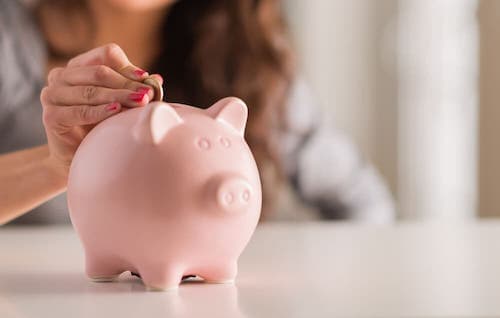 Photo of a woman putting change into a piggy bank