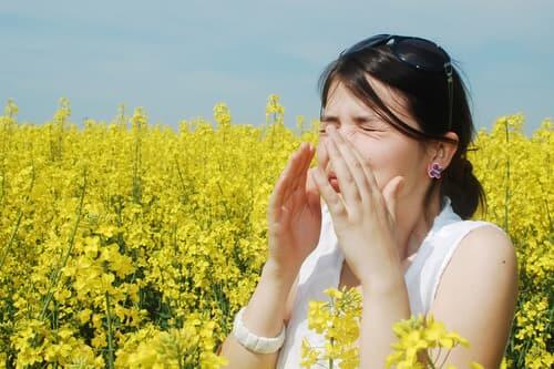 Woman suffering from allergies in field of flowers