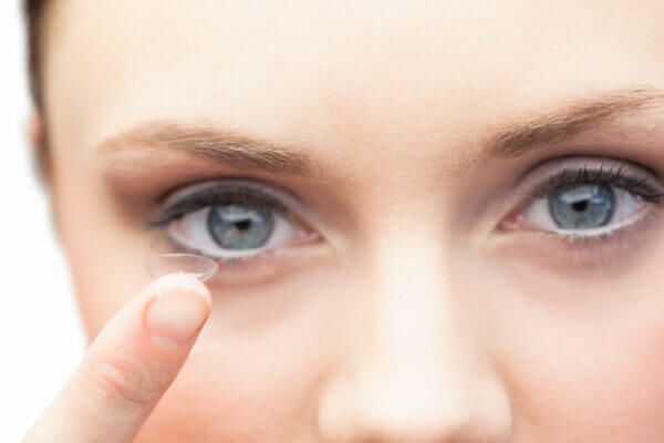Closeup of young woman with contact lens on her finger