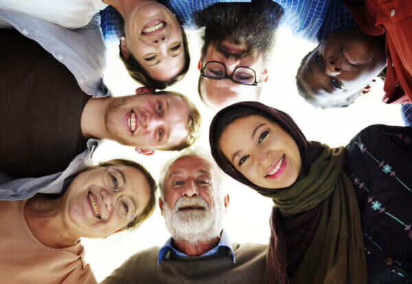 Group of multi-age, multi-ethnic people standing in a circle looking down