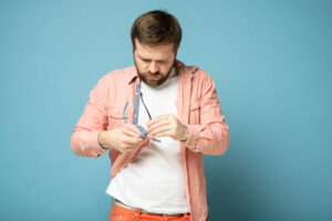 man cleaning off his glasses with his shirt