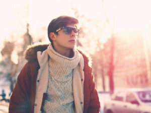 man walking down the street while wearing winter coat and sunglasses