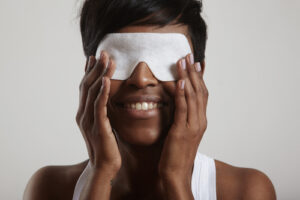 woman applying warm compress to her eyes