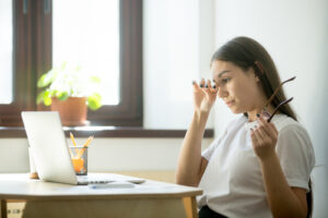 woman rubbing her eyes while sitting at desk and using laptop