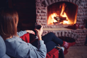 woman sitting in front of fire place while holding glass of wine